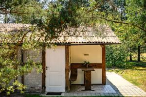 a small hut with a white door and a table at Place near beach in Pērkone