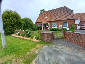 a brick house with a fence in the yard at FeWo Düver in Loxstedt