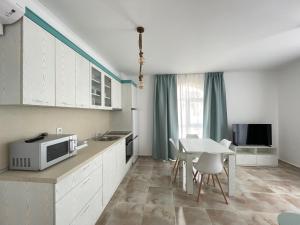 a kitchen with white cabinets and a table with a microwave at Izida Palace Apartments in Sunny Beach