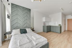 a bedroom with a large bed and a kitchen at Grand Apartments - Bastion Wałowa Studio in Gdańsk