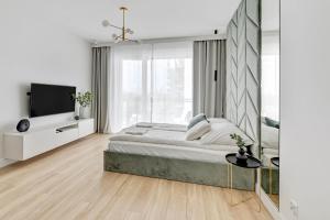 a white bedroom with a bed and a flat screen tv at Grand Apartments - Bastion Wałowa Studio in Gdańsk