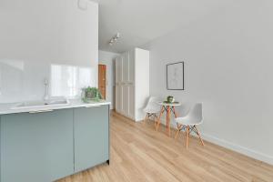 a kitchen with white counters and a table and chairs at Grand Apartments - Bastion Wałowa Studio in Gdańsk