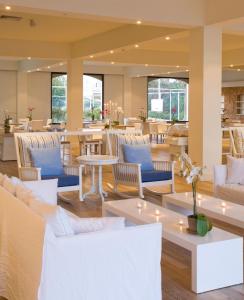 a lobby with white chairs and tables and tablesktop at Sandy Beach Hotel & Spa - ex Sentido in Larnaca