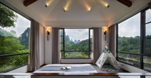 a room with large windows and a bed with a tent at Li River Resort in Yangshuo