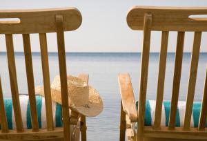 two chairs with a straw hat sitting next to the water at Sandy Beach Hotel & Spa - ex Sentido in Larnaca