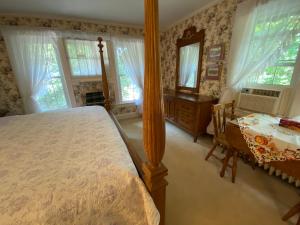 a bedroom with a bed and a table and windows at Bernard Gray Hall Bed and Breakfast in Niagara-on-the-Lake