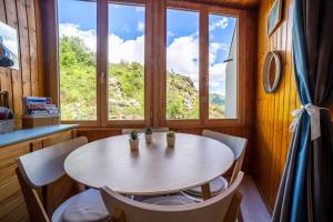 einen Tisch und Stühle in einem Zimmer mit Fenster in der Unterkunft L'Eclose - Alpe d'Huez in Huez