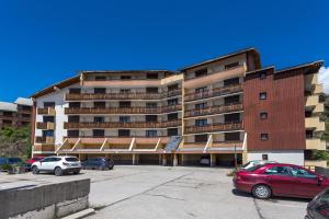 duży apartamentowiec z samochodami zaparkowanymi na parkingu w obiekcie L'Eclose - Alpe d'Huez w mieście LʼHuez