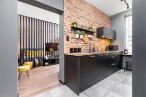a kitchen with black cabinets and a brick wall at Old Town Studio Good Vibes by Renters in Krakow