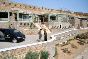 2 personnes debout devant un bâtiment avec une voiture dans l'établissement EmGard Suites Kythnos, à Kythnos