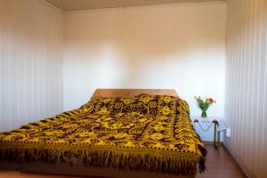 1 dormitorio con 1 cama con manta amarilla en Chata Skrzata en Sztabin