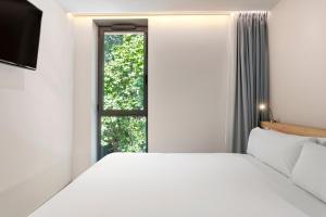 a bedroom with a white bed and a window at B&B HOTEL Lisboa Montijo in Montijo +42 photos