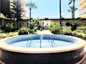 a fountain in the middle of a building with palm trees at Rentcostadelsol Fuengirola Doña Sofia 3D in Fuengirola