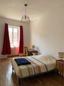 1 dormitorio con cama, mesa y ventana en Les Jardins d'Élise, calme et verdure à Lure, en Lure