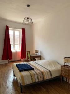 a bedroom with a bed and a table and a window at Les Jardins d'Élise, calme et verdure à Lure in Lure