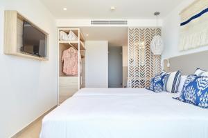 a bedroom with a white bed and a flat screen tv at Can Salia in San Antonio Bay