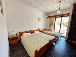 a bedroom with two beds and a window at Afroditi Pension in Archangelos
