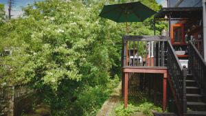 un balcón con sombrilla junto a una casa en River Cottage at Old Post Office en Bardon Mill