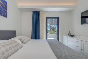 a bedroom with a white bed and a window at VILLA ELEMENTA - A peaceful retreat in Milna +37 photos
