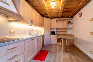 una cucina con armadi bianchi e soffitto in legno di Ospitalità Diffusa Laste Dolomites Cèsa del Bèrba Jaco a Rocca Pietore