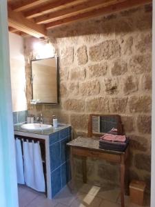 a bathroom with a sink and a stone wall at Domaine du Clap in Pranles