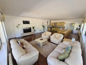 a living room with white couches and a kitchen at Quinta Manuel Santo in Nazaré