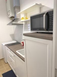 een witte keuken met een magnetron en een wastafel bij Domina Living Apartments - Presepe in Bisceglie