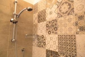 een douche in de badkamer met tegels op de muur bij Domina Living Apartments - Presepe in Bisceglie