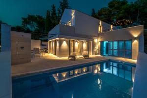 a house with a swimming pool at night at VILLA ELEMENTA - A peaceful retreat in Milna