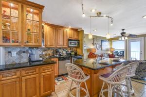 a kitchen with wooden cabinets and a island with bar stools at Seascape 1209 Condo in Galveston