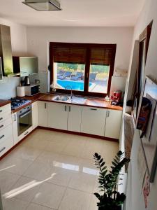 cocina con armarios blancos, fregadero y ventana en Villa Cvita, en Povljana