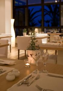 a table with glasses and a potted plant on it at Sandy Beach Hotel & Spa - ex Sentido in Larnaca