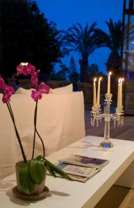 a table with pink flowers in a vase and candles at Sandy Beach Hotel & Spa - ex Sentido in Larnaca