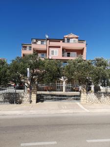 a pink building with a fence in front of a street at Marija in Šibenik