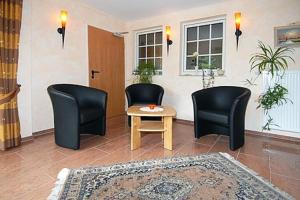 a living room with two chairs and a table at Hotel-Pension Störtebeker in Bensersiel