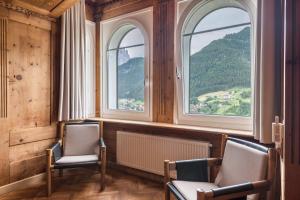 two chairs in a room with two windows at Villa Martiner Apartments Moritz in Ortisei