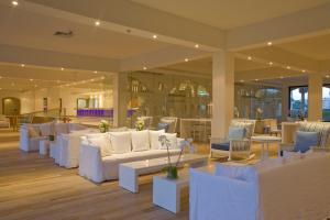 a large room with white couches and tables at Sandy Beach Hotel & Spa - ex Sentido in Larnaca