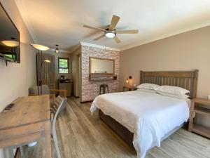 a bedroom with a bed and a table and a fireplace at Loerie Guest Lodge in George