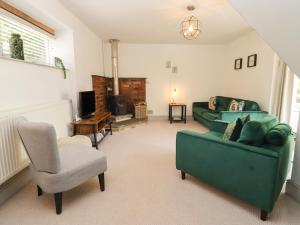 a living room with a green couch and a chair at The Coach House in Ross on Wye