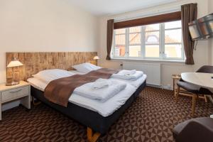 a bedroom with a bed and a desk and a window at Foldens Hotel in Skagen