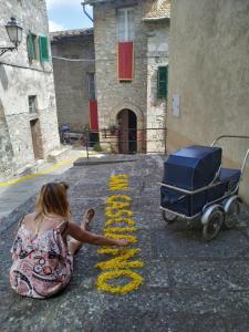 una mujer sentada en la calle con un cochecito de bebé en Casa Pizzinelli, en San Casciano dei Bagni