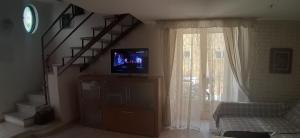 salon z telewizorem na komodzie ze schodami w obiekcie Casetta Iacono appartamento Aenaria w mieście Ischia