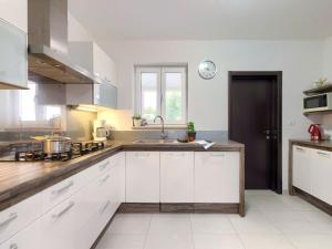 a kitchen with white cabinets and a clock on the wall at Holiday Home Villa Vela - PUL451 by Interhome in Šišan