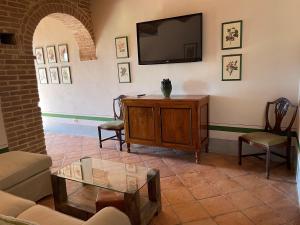 uma sala de estar com um sofá e uma televisão na parede em Altesino Suites em Montalcino