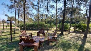 una mesa de picnic y sillas en un parque con árboles en Complejo Cabañas Piriápolis en Piriápolis