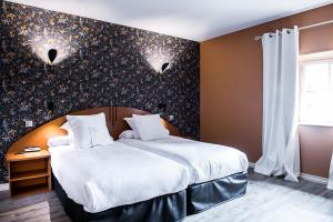 um quarto com uma cama grande e lençóis brancos em Hostellerie la Ferme du Poulet et son restaurant em Villefranche-sur-Saône