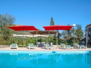 a pool with two umbrellas and chairs and a group ofitures at Holiday Home Villa Kikiza - MKA520 by Interhome in Vrgorac