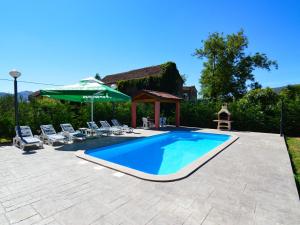 a swimming pool in a yard with chairs and an umbrella at Apartment Baba Nevenka - MKA526 by Interhome in Vrgorac