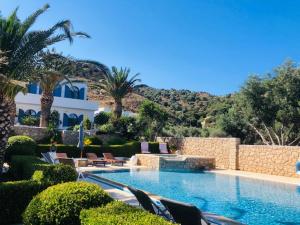 ein Schwimmbad mit Stühlen und Bäumen und ein Gebäude in der Unterkunft La Bastide in Skyros