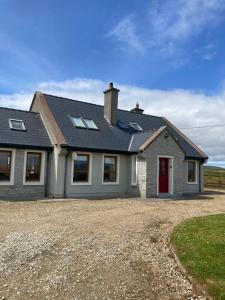 a house with a red door on a gravel driveway at Broadhaven Bay View Private House in Belmullet